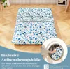 A futon mattress with a blue floral pattern is laid out on a wooden floor. A circular inset shows a hand placing the mattress into a washing machine. Náhled obrázku produktu