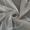 A close-up shot of a beige fabric with a white abstract pattern, folded into a swirl. Produktbild-Vorschau