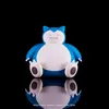 A Snorlax figurine is shown against a black background, with its reflection visible below. Náhled obrázku produktu
