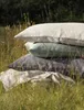 A stack of pillows in a grassy outdoor setting. Produktbild-Vorschau
