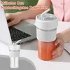 A person is using a laptop while a portable smoothie mixer is on the desk. Produktbild-Vorschau