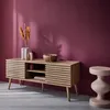 A wooden TV stand with slatted doors is placed against a purple wall, with decorative items on top and a small stool to the side. Anteprima dell’immagine prodotto