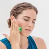 A woman is using a green foam roller on her cheek. Anteprima dell’immagine prodotto