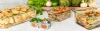 A collection of glass food storage containers filled with various prepared meals, set against a backdrop of fresh vegetables. Produktbild-Vorschau