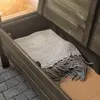 A wooden storage bench with a blanket inside, placed on a cobblestone patio. Voir les images du produit