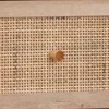 A close-up view of a wooden drawer knob on a rattan woven surface. Produktbild-Vorschau