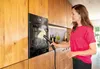 A woman is cleaning an oven with a steam cleaner in a modern kitchen. Podgląd zdjęcia produktu