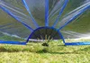 Close-up view of the base of a transparent pool cover with blue trim, resting on grass. Produktbild-Vorschau