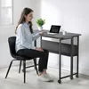 A woman is sitting at a folding desk and working on a laptop. Produktbild-Vorschau