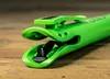 A close-up shot of a green tool with a black component inside, resting on a wooden surface. Produktbild-Vorschau