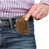 A person is putting a brown leather wallet into their jeans pocket. Produktbild-Vorschau