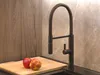 A modern kitchen sink area with a black faucet, a wooden cutting board, and two apples. Podgląd zdjęcia produktu