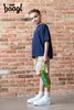 A young boy stands in front of a brick wall, holding a green water bottle. Anteprima dell’immagine prodotto