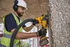 A construction worker is using a DeWALT cordless masonry saw to cut into a concrete pillar. Voir les images du produit