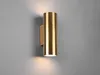 A brass cylinder wall light mounted on a gray wall, with light emanating from the top and bottom. Produktbild-Vorschau