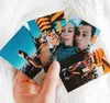 A hand holding several printed photos of people at an outdoor event. Podgląd zdjęcia produktu