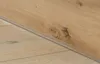A close-up view of a wooden floor with a metal transition strip. Produktbild-Vorschau