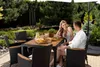 A couple is enjoying a meal at a table in a garden. Náhľad obrázku produktu