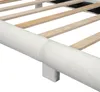 A close-up view of the side of a white upholstered bed frame with wooden slats visible underneath. Náhled obrázku produktu