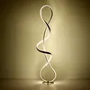 A modern, sculptural floor lamp with a twisted, ribbon-like design, illuminated against a gradient background. Produktbild-Vorschau