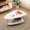 A white triangular coffee table with two shelves, placed on a rug in a living room setting. Voir les images du produit