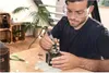 A man is using a Dremel rotary tool to work on an old camera. Anteprima dell’immagine prodotto