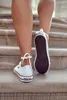 A person's legs are shown walking up a set of stairs, wearing white sneakers. Voir les images du produit