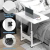 A white adjustable height rolling table with a laptop and a cup of coffee on it, placed next to a bed. Produktbild-Vorschau