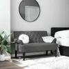 A dark gray tufted bench with a white round pillow and a white throw blanket is placed in a bedroom setting next to a bed. Produktbild-Vorschau
