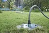 A close-up shot of a Kärcher pump connection piece with a check valve, installed in a garden with a sprinkler system in the background. Náhľad obrázku produktu