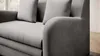 A close-up view of a gray sofa, showing the texture of the fabric and the rounded armrest. Produktbild-Vorschau