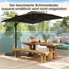 An outdoor patio scene with a wooden table and benches, a large black umbrella, and plants. Podgląd zdjęcia produktu