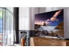 A modern living room with a large television displaying a scenic image, placed on a wooden cabinet. Produktbild-Vorschau