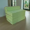 A green folding mattress is shown in a room with a window in the background. Náhled obrázku produktu