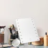 A makeup mirror with LED lights and various makeup brushes and products on a vanity. Voir les images du produit