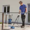 A man is using a pressure washer on a patio. Produktbild-Vorschau