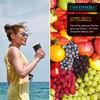 A split image showing a woman holding a smoothie maker on a beach and a close-up of various fruits. Produktbild-Vorschau