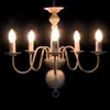 A white chandelier with five candle-shaped bulbs against a black background. Voir les images du produit