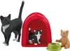 A collection of cat figurines, including a large black and white cat, a smaller black and white kitten inside a red cat house, and a ginger kitten next to a green food bowl. Podgląd zdjęcia produktu