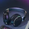 A pair of black over-ear Bluetooth headphones with metallic accents, resting on a textured dark surface with subtle purple and blue lighting. Produktbild-Vorschau