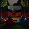 People watching a movie outdoors on a projector screen, sitting on beanbag chairs. Voir les images du produit