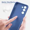 A hand is touching the matte surface of a blue phone case, highlighting its soft grip texture. There is also a small pile of white fluffy material in the background. Produktbild-Vorschau