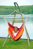 A young woman sits in a hammock chair by a lake. Náhled obrázku produktu