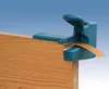 A close-up shot of a teal-colored edge banding trimmer tool being used on the edge of a wooden board. Anteprima dell’immagine prodotto