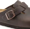 A close-up view of a brown Birkenstock clog, focusing on the buckle and strap. Produktbild-Vorschau