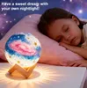 A young girl sleeping next to a galaxy-themed night light on a bed. Produktbild-Vorschau