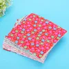 A stack of small, square fabric pieces with a floral print, laid on a blue surface. Náhľad obrázku produktu
