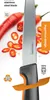 A close-up of a knife with red chili peppers in the background. Podgląd zdjęcia produktu