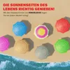 Several colorful beach umbrellas are arranged on a sandy beach with waves in the foreground. Produktbild-Vorschau
