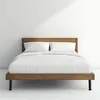 A bed with white bedding in a room with a white wall. Produktbild-Vorschau